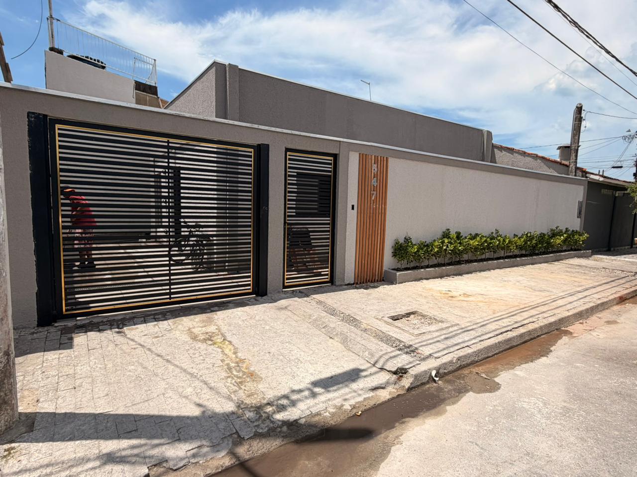Fachada executada com portão ripado e jardim linear